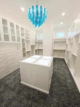 White custom closet with blue chandelier and elegant built-in storage